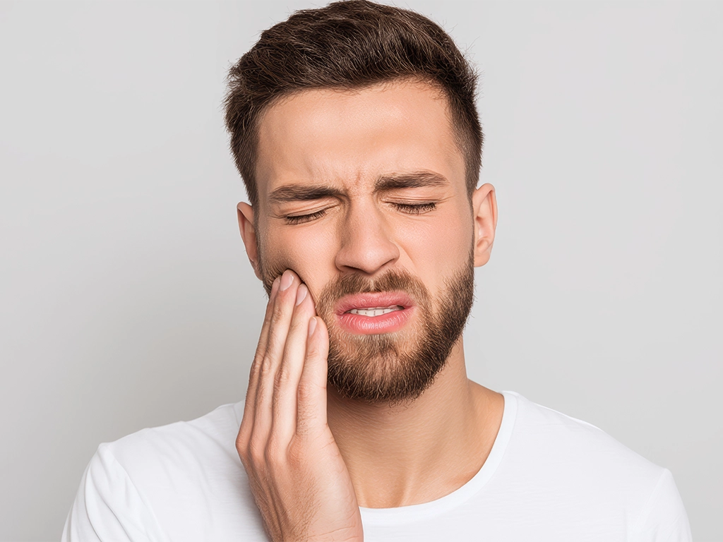 closeup of young man with toothache holding jaw tooth pain_LG